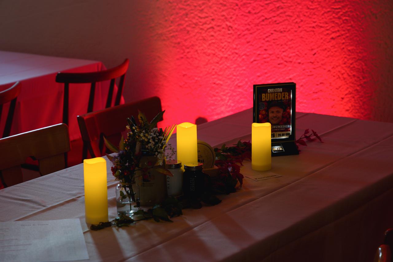 Kerzen und Tischdekoration vor einer rot beleuchteten Wand